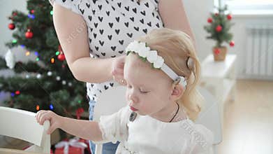 Concept of hearing impairment and their treatment. Young Mother connect a cochlear implants to her daughter's head