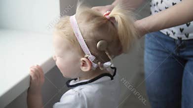 Concept of hearing impairment and their treatment. Young Mother connect a cochlear implants to her daughter's head