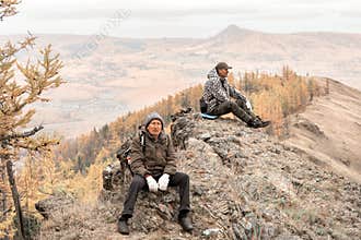 two mature tourists at the top of the ridge admire the Ural mountains and taiga