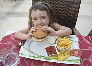 A little girl with an appetite eats a burger