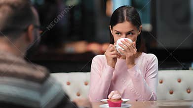 Happy female smiling drinking tea at cafe talking with male on date. Medium shot on RED camera
