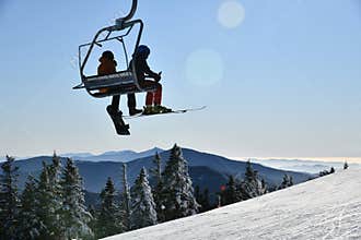 Chairlift with people at Stowe Ski Resort in Vermont, view to the Mansfield mountain slopes