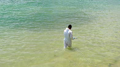 Man in white protective clothing cleaning ocean from oil spill disaster