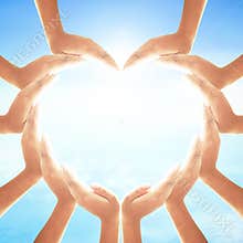 Circle of Diverse Hands Creating Heart Shape against Bright Ethereal Blue Sky