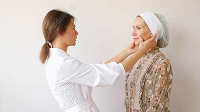 Professional cosmetologist examines face after operation