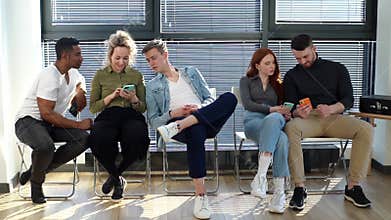 Happy diverse young diverse multiethnic men and women sharing social media news using mobile gadgets.