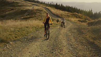 Woman on bicycle looking back at man. Bicyclists exercising in landscape