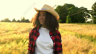 Mixed race African American girl teenager female wearing cowboy hat in field at sunset