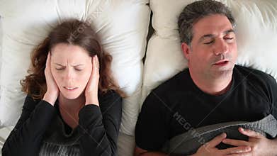 Woman suffering from man snoring in bed