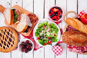 Summer picnic food table scene. Top view over a white wood background.