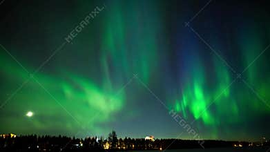 Green aurora northern light dancing under a starry and moonlit sky on a frozen lake in a nordic country