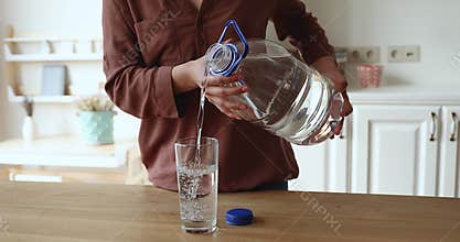 Closeup female holding plastic bottle pouring still water into glass