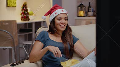 Cheerful woman watching television and eating chips