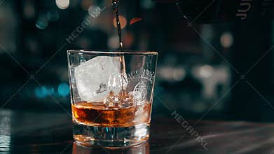expensive, exquisite whiskey from a bottle is poured into a glass of ice.