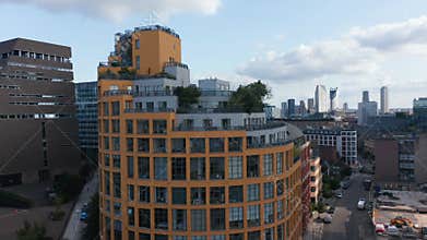 Crane up footage of Bankside Lofts apartment building. Rounded building with colourful facade. Group of skyscrapers in