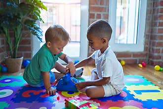 Adorable toddlers playing around lots of toys at kindergarten
