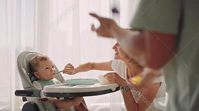 Dad entertains the baby during feeding. The father juggles while the mother feeds the baby. The problem of feeding a