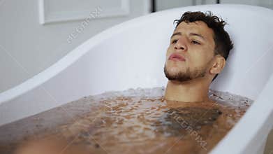 Man sits with closed eyes in the bath with ice cubes for recovery