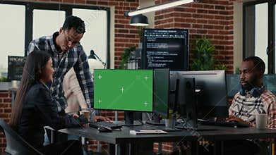 Two software developers analyzing source code looking at green screen chroma key mockup with coworker sitting at desk
