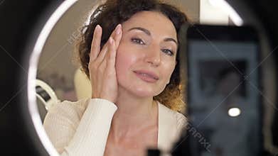 Beautiful middle aged woman demonstrates the application of a moisturizing and nourishing cosmetic product for skin care