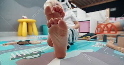 Cute children foot closeup moving fingers sitting in kid room on evening