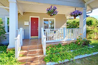 Grey old house front porch exterior with red door.