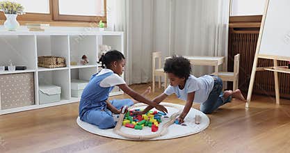 Afro American kids elder sister younger brother constructing from bricks