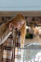 Young woman looking at the shop showcase and jewelry to look at it closer