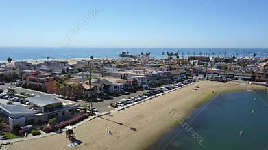 Stunning aerial footage of the vast blue ocean water with people standing on paddle boat on the water and beach front homes