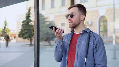 A blind man speaks on the phone at a stop bus