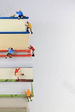 Miniature toy climbers ascend a stack of books.