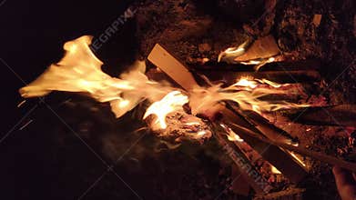one sausage on a stick in camp fire at night, vertical video