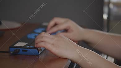 Close-up hands of person with blindness disability using computer keyboard and braille display or braille terminal a technology
