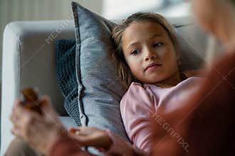 Grandmother taking care of her ill grandchild lying on sofa