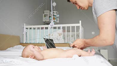 Young father watches instructional video to change diaper