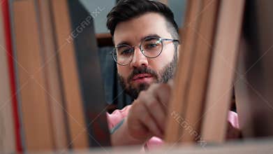 Closeup face hipster student bearded guy choosing vintage paper book wooden shelf at public library