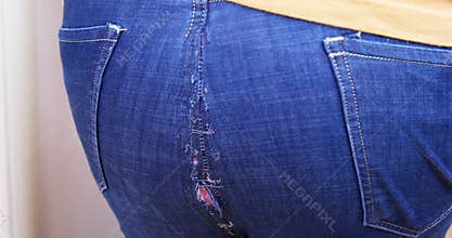 Jeans crack and part at seam after tilting person. Hand checks hole on ass on jeans.