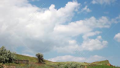 Timelapse of clouds flying in the sky over bushes, plants, trees and cliffs in summer