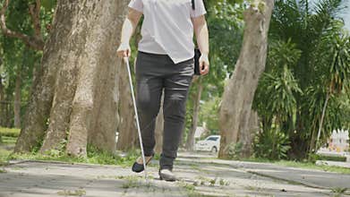 Asian woman with blindness disability walking on sidewalk contain tactile paving guide blocks using long white cane or blind cane
