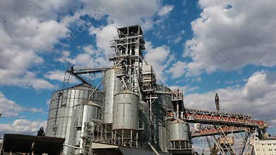 Sea grain elevator at seaport berth with moored bulker ship. Grain-drying handling terminal, conveyors. Commercial seed