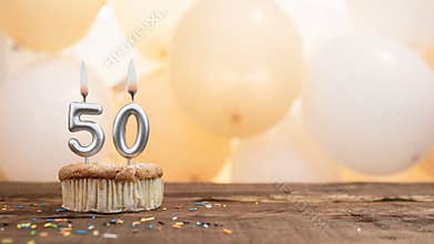 Happy birthday card with candle number 50 in a cupcake against the background of balloons. Copy space happy birthday for fifty