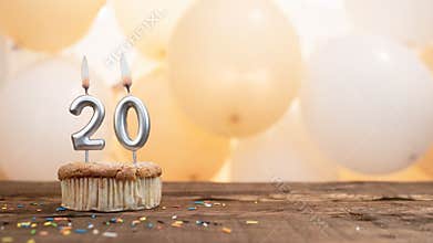 Happy birthday card with candle number 20 in a cupcake against the background of balloons. Copy space happy birthday for twenty