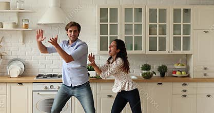 Emotional excited young caucasian family couple dancing in kitchen.
