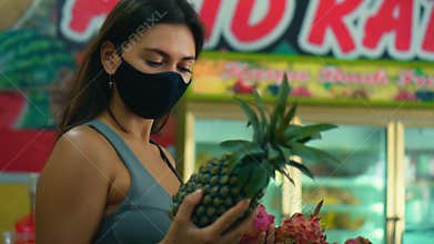 European girl chooses organic fruits in a store holding a pineapple in her hand