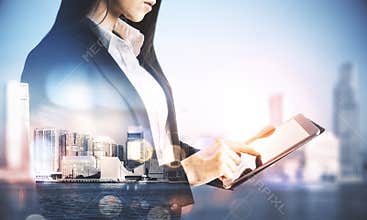 Pretty businesswoman using tablet on abstract city background