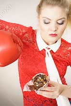 Woman fighting off bad food, boxing chocolate cake