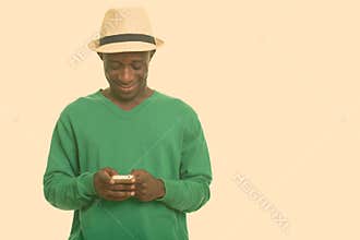 Young happy African man smiling and using mobile phone