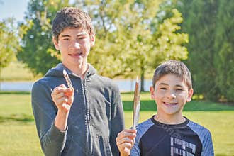 Boys Holding Up Bird Feathers on Nature Hike