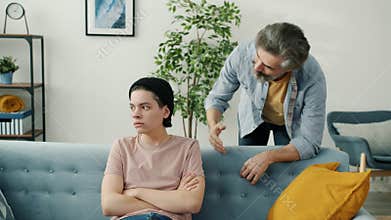 Abusive dad yelling at unhappy teenage boy fighting with child indoors in apartment