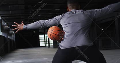 African american man and woman standing in an empty building playing basketball